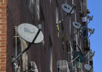 DirecTV satellite dishes are mounted outside an apartment building. (Courtesy/Carlos Becerra/Bloomberg)